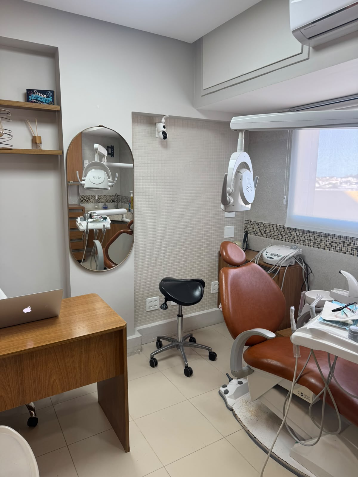 Consultório com cadeira odontológica, espelho e iluminação natural
