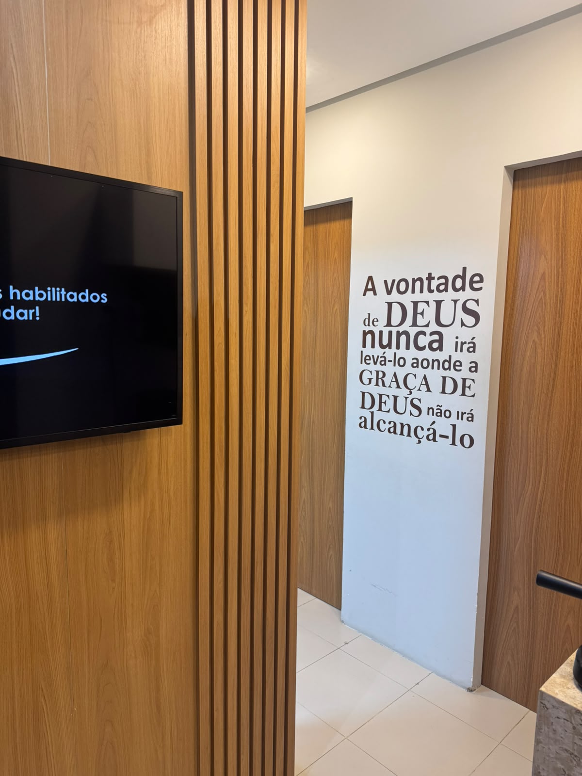 Corredor da clínica com painel de madeira e frase na parede